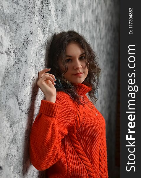 Sensual beautiful girl posing in red sweater. Girl with long curly hair.