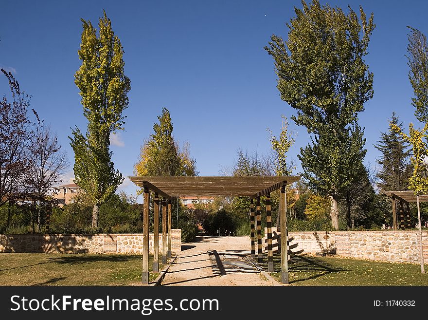 A light, wooden awning or covering over a walkway in a park. A light, wooden awning or covering over a walkway in a park.