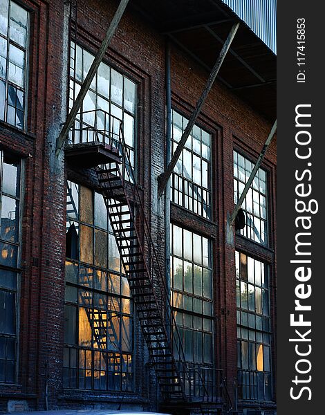 Old abandoned textile factory building with large windows and fire escape stairs at sunset in Lodz,Poland. Old abandoned textile factory building with large windows and fire escape stairs at sunset in Lodz,Poland