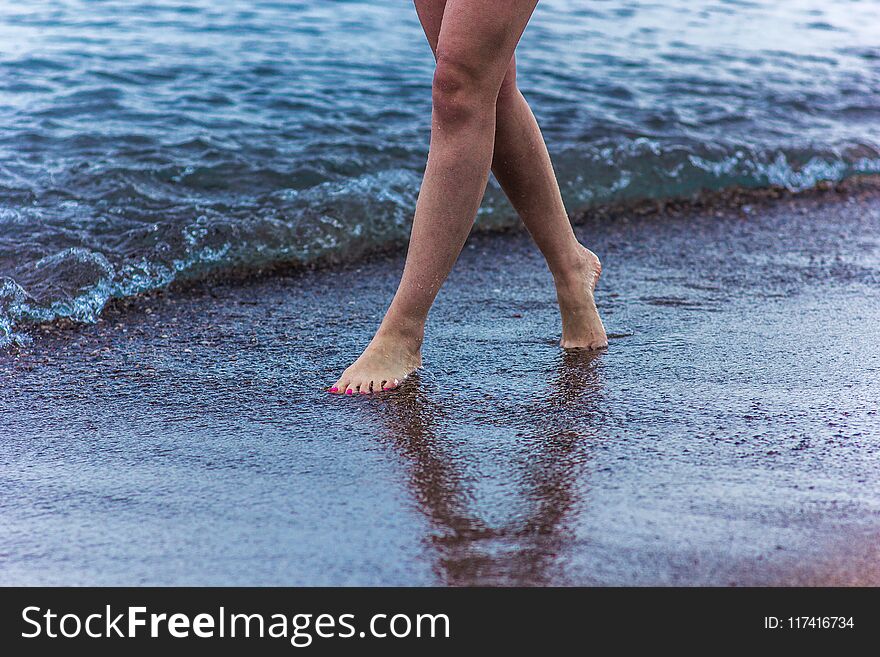 The girl is walking along the seashore, beautiful legs