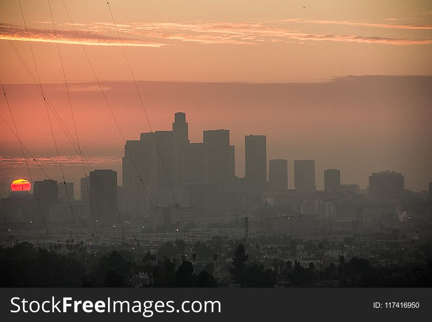 Dramatic Sunset at Los Angeles downtown Skyline. We can also see East LA in the foreground and some power lines.