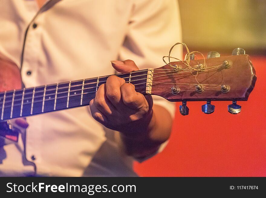 Musician playing acoustic guitar on stage music band in the night at nightclub