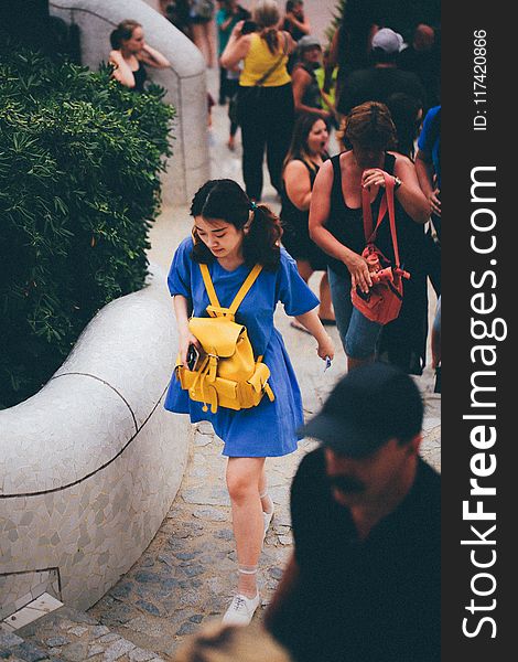 Woman in Blue Dress With Yellow Knapsack Walking Near People
