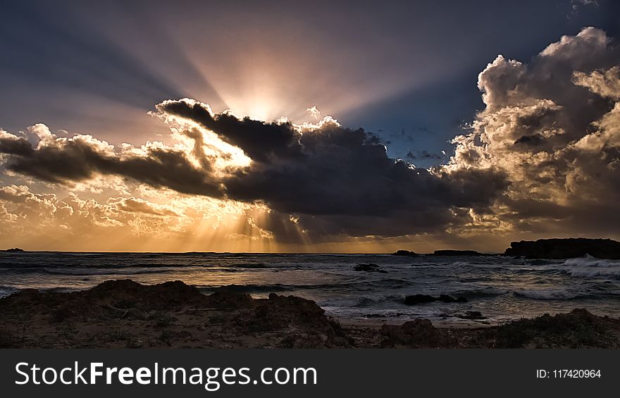Body of Water Under Clouds With Sun Rays