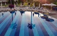 Beautiful Reflection In Clear Water Of Blue Swimming Pool With Chaise-longues In Luxury Resort Hotel Royalty Free Stock Photography