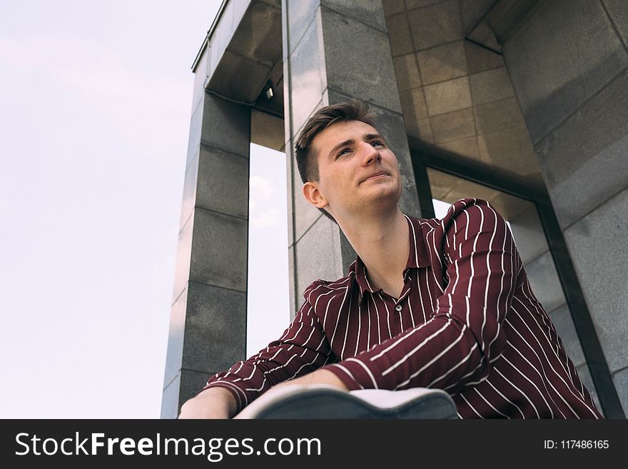 Man In Red And White Striped Dress Shirt Posing Near Wall