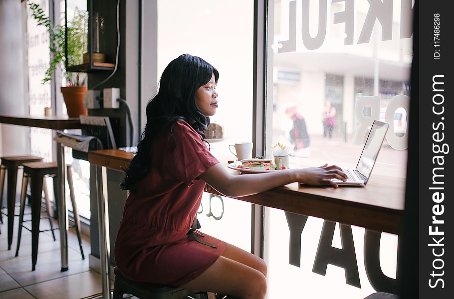 Woman in Red Dress Using Laptop on Table