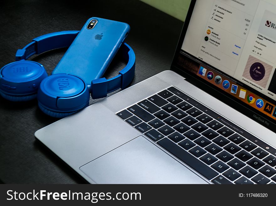 Macbook Pro Beside Blue Wireless Headphones