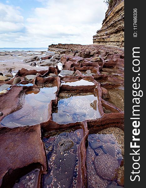 Calm Body Of Water Beside Rocks