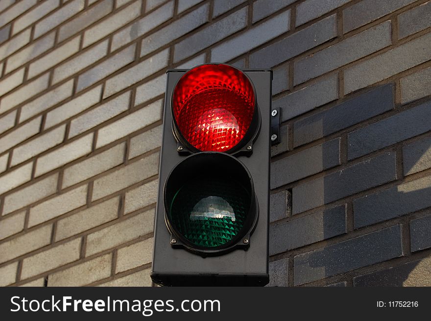 A red stoplight with a wall in the back