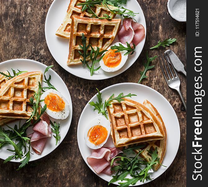 Delicious savory breakfast on a wooden background - boiled eggs, potato waffles and ham, top view