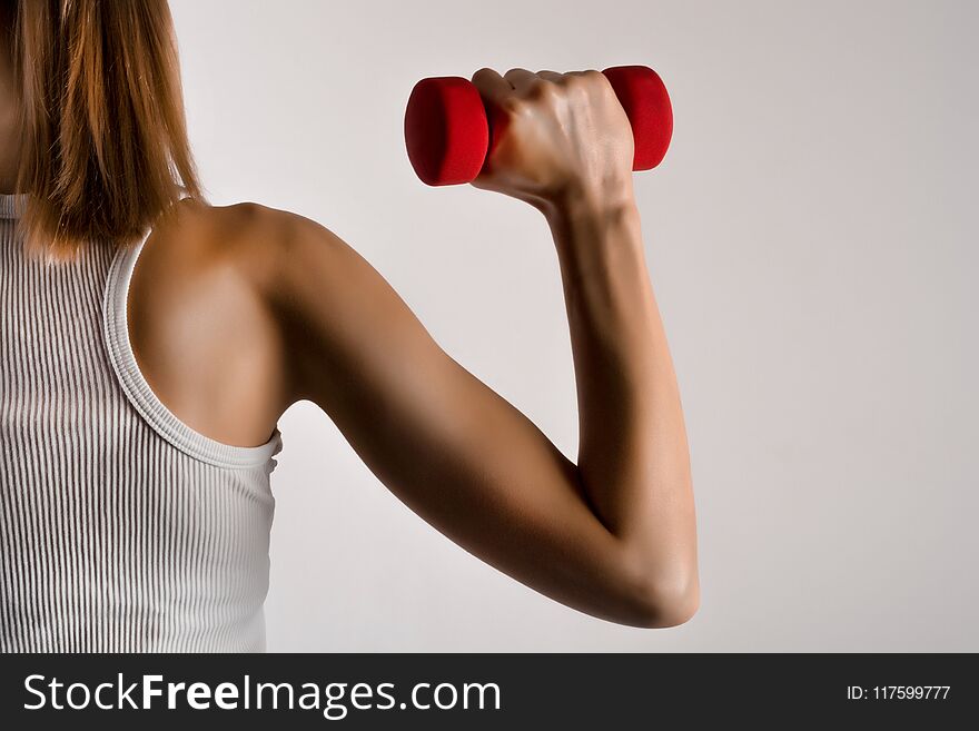 Fitness model woman hand with yellow dumbbell on gray studio background. Bodybuilding, healthy lifestyle and sport concept. Low key and close up