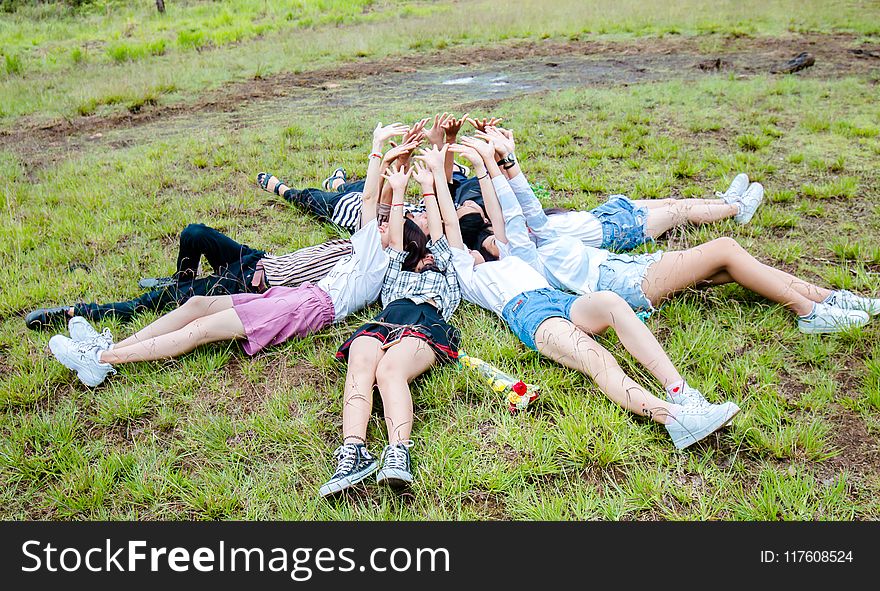 Group of Friends Form in Circle While Lying on the Grass While Hands on Top