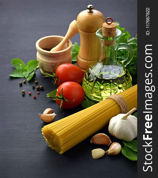 Preparing to cook pasta. Spaghetti, tomatoes, garlic, cheese grater,greens and spices on black background top view. Preparing to cook pasta. Spaghetti, tomatoes, garlic, cheese grater,greens and spices on black background top view.