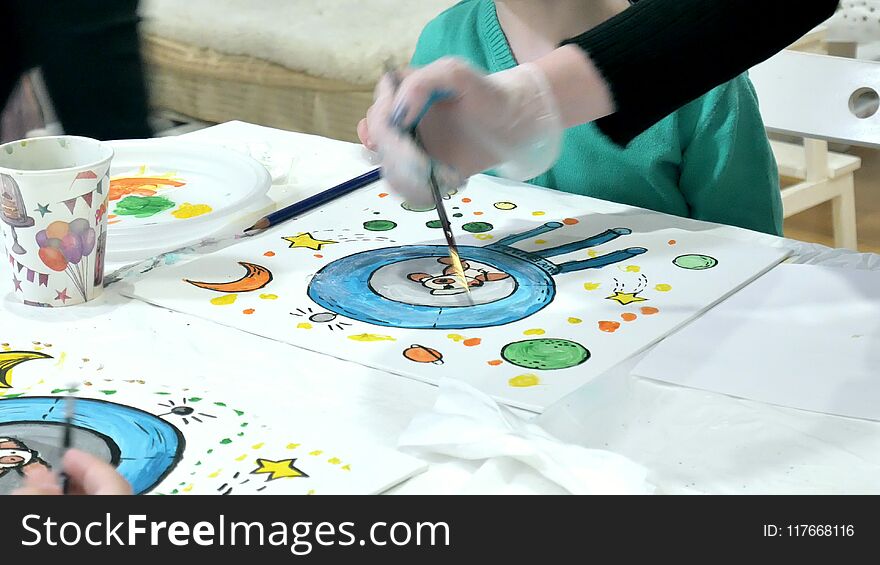 Children boys sitting together around the table in classroom and drawing. With them is their young and beautiful teacher.. 4k