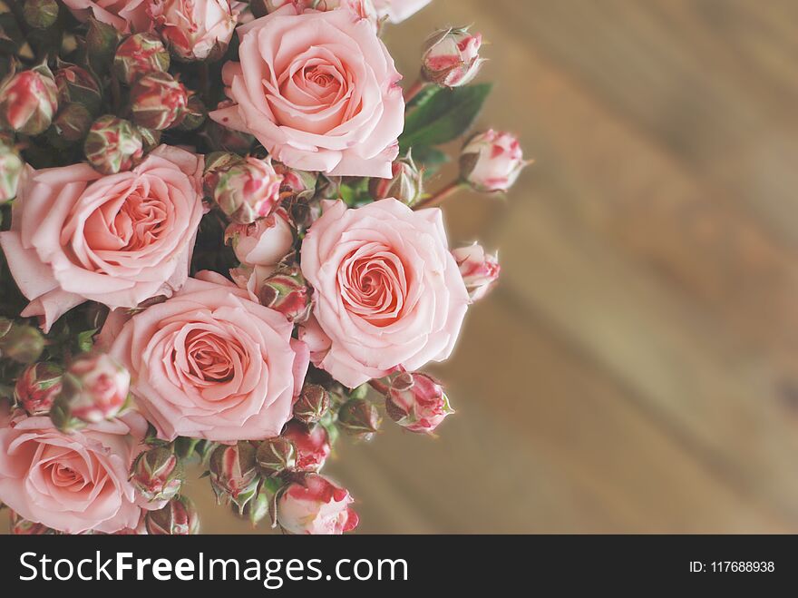 Pink roses bouquet over wooden table. Top view with copy space. Toned. Pink roses bouquet over wooden table. Top view with copy space. Toned
