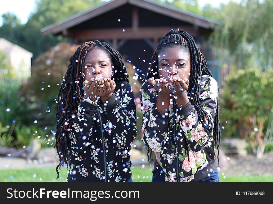 Two Girls Blowing Petals of Flowers Off Their Hands