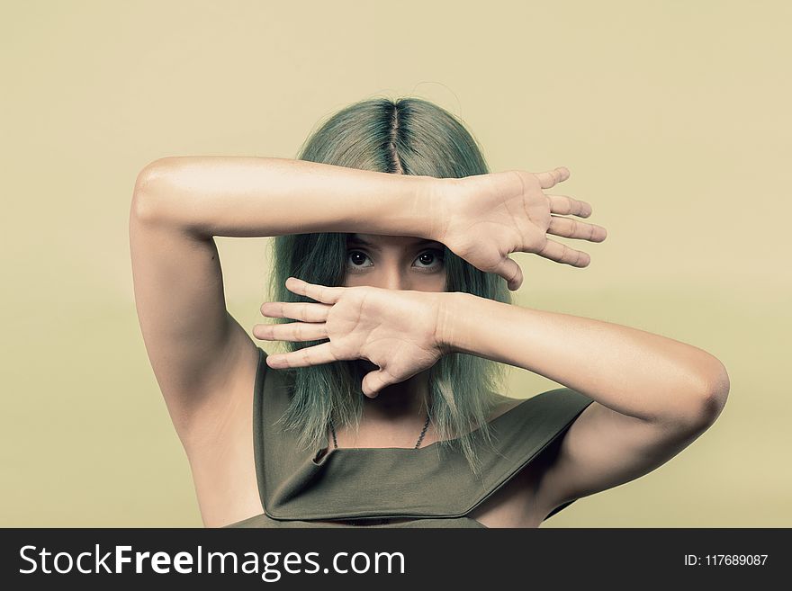 Woman Wearing Green Sleeveless Top Covering Her Face but Eyes With Both Hands