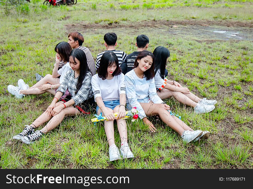 Men and Women Sitting on Grass Forming Circle of Friends