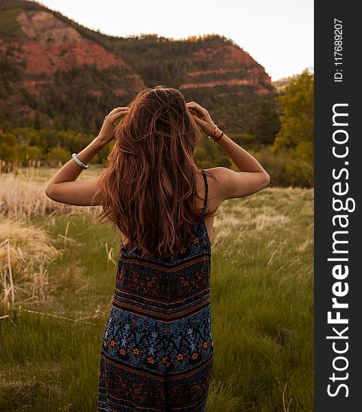 Woman Wearing Red and Blue Floral Dress Standing Beside Mountain