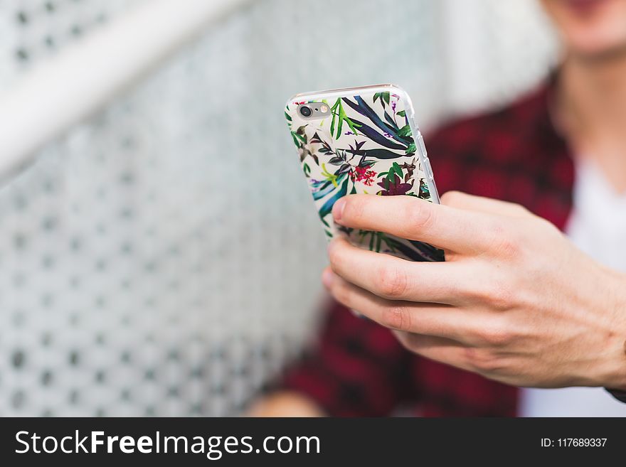 Person Holding Smartphone With White and Green Floral Case