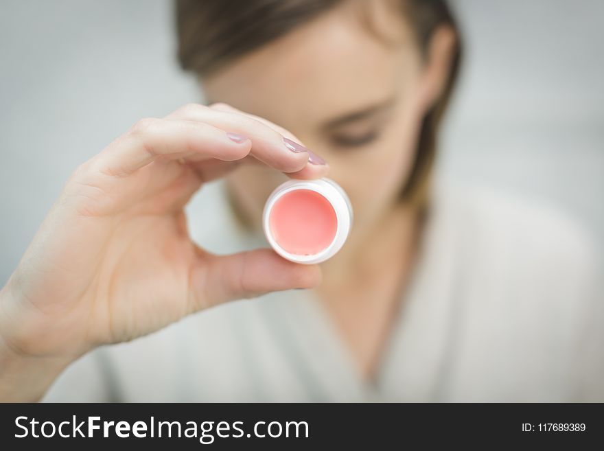 Person Holding Round White and Pink lipbalm