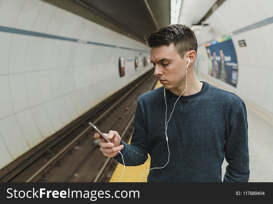 Man looking at a phone with earphones on