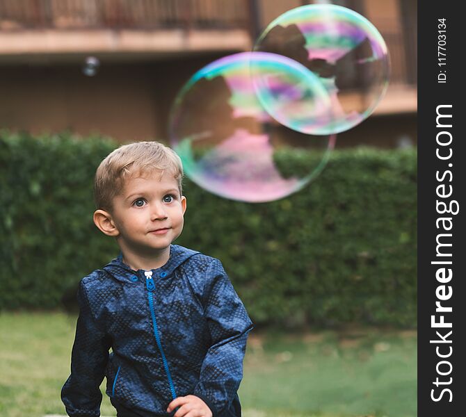 Beautiful baby boy enjoying blowing big soap bubbles in the autumn. Happy childhood concept. Beautiful baby boy enjoying blowing big soap bubbles in the autumn. Happy childhood concept.