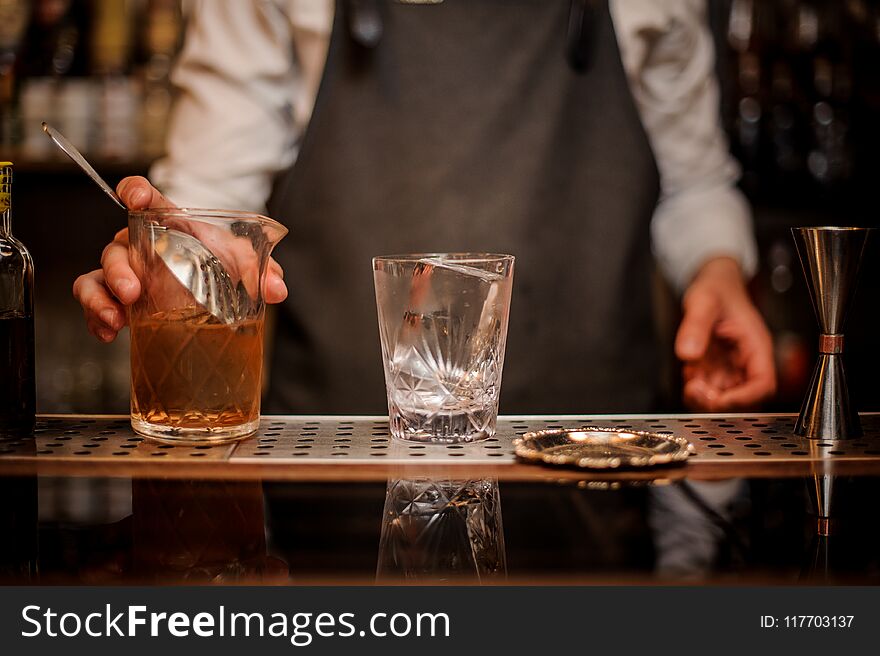 Bartender holding a mixing glass with an alcoholic drink