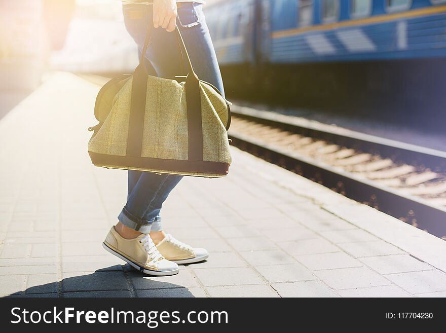 Woman holding a bag at a train station. Passenger waiting train.