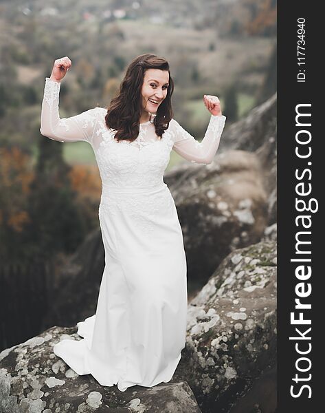 Beautiful happy bride outdoors in a forest with rocks. Wedding perfect day.