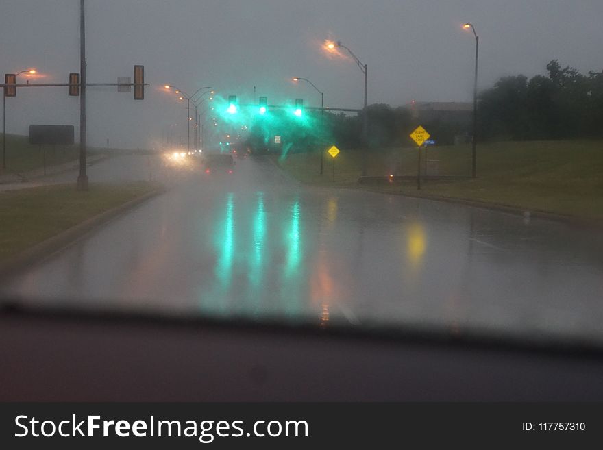 A photo of some green street lights in the hard rain blurry. A photo of some green street lights in the hard rain blurry