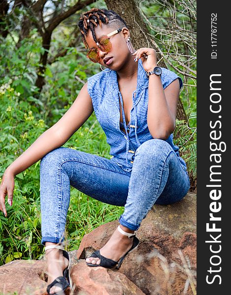 Woman Wearing Denim Pants Sitting On Brown Stone Near Plants