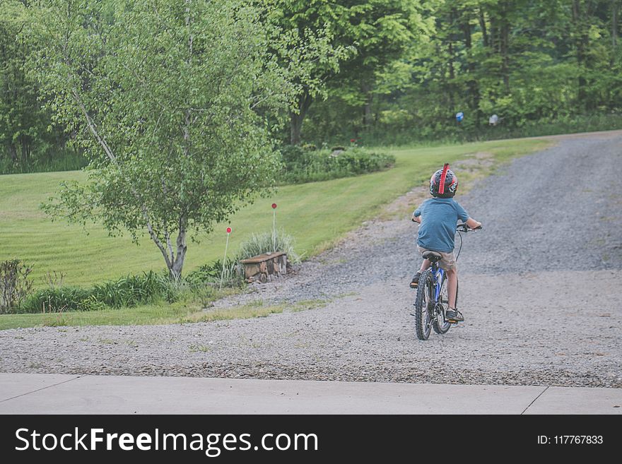 Boy Wearing Blue T-shirt and Beige Shorts Outfit Riding on Black Bicycle at Daytime