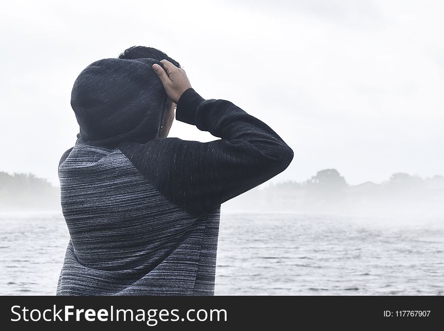 Person in Black and Grey Raglan Hoodie Near Body of Water