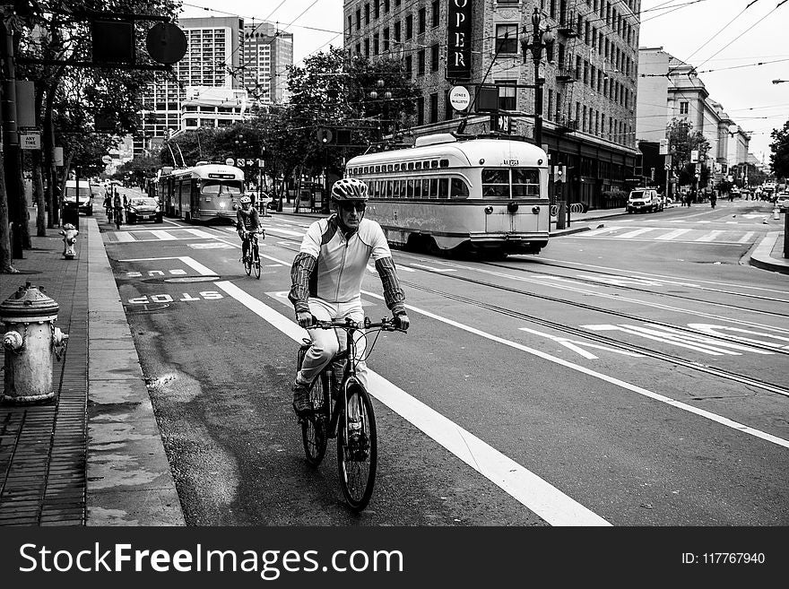 Grayscale Photo of Man Riding Bicycle on Street
