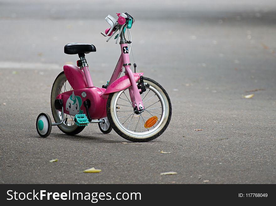 Pink Bike With Training Wheels on Gray Pave Road
