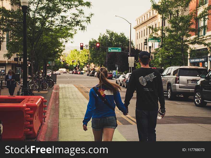 Man and Woman Holds Hands While Walking