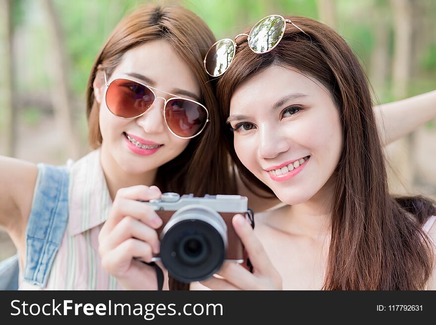 Two beauty women take camera and go travel happily in the forest. Two beauty women take camera and go travel happily in the forest