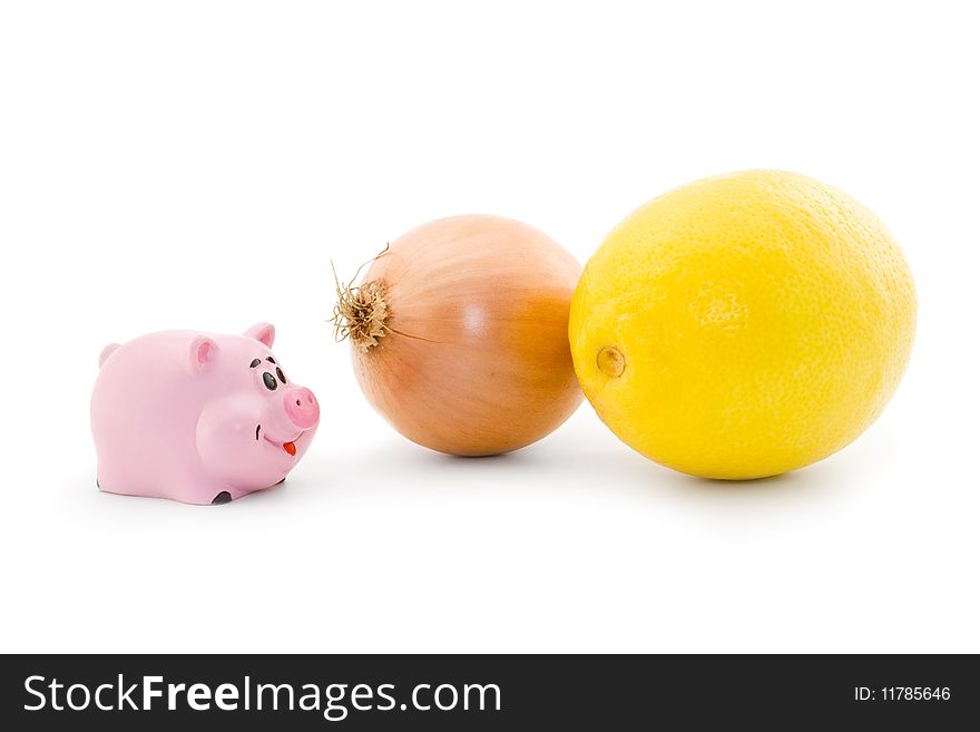 Small pink piggy looks at onion and lemon. Small pink piggy looks at onion and lemon