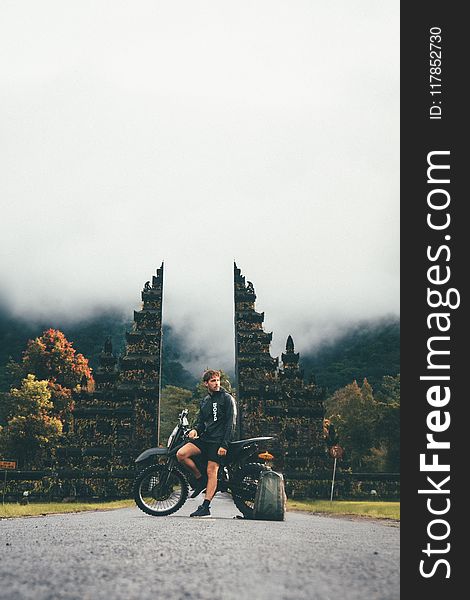 Photo Of Man Sitting On Motorcycle Near Tower