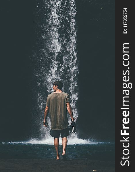 Man Wearing Gray Shirt Walking Near Waterfalls
