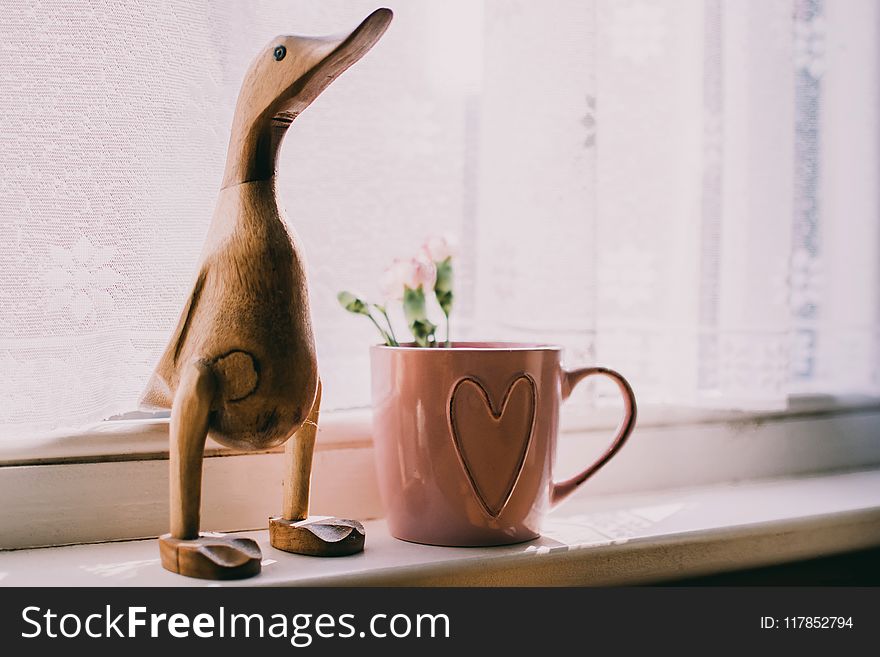 Brown Wooden Duck Figurine Near Brown Ceramic Mug