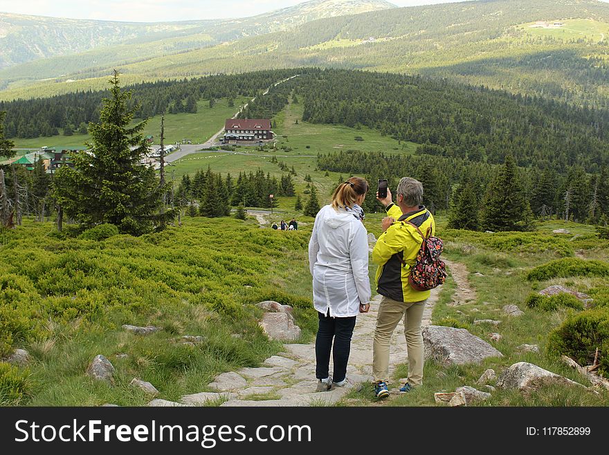 Woman Beside Man on Top of Mountain Taking Selfie