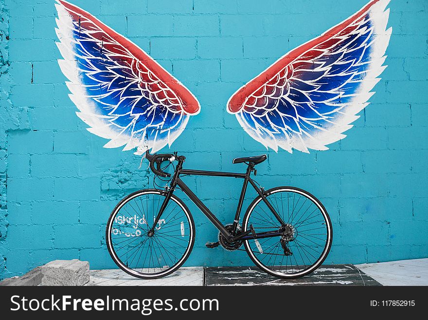 Black Road Bike Leaning on Red-blue-and-white Wing Graffiti Wall
