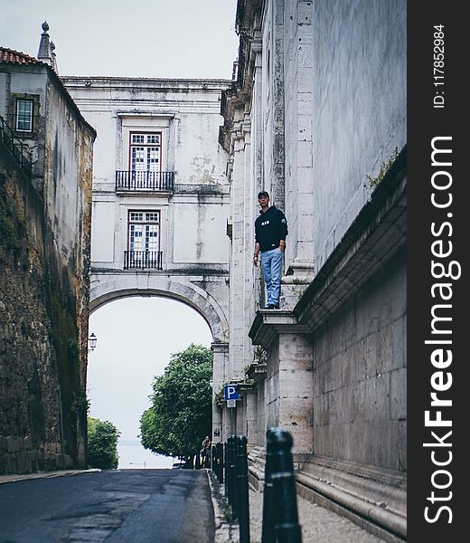 Man Wearing Black Pullover Hoodie Standing On Beside Beige Concrete Building