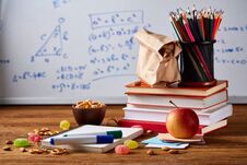 Back To School Concept, School Supplies, Biscuits, Packed Lunch And Lunchbox Over White Chalkboard, Selective Focus. Stock Photo