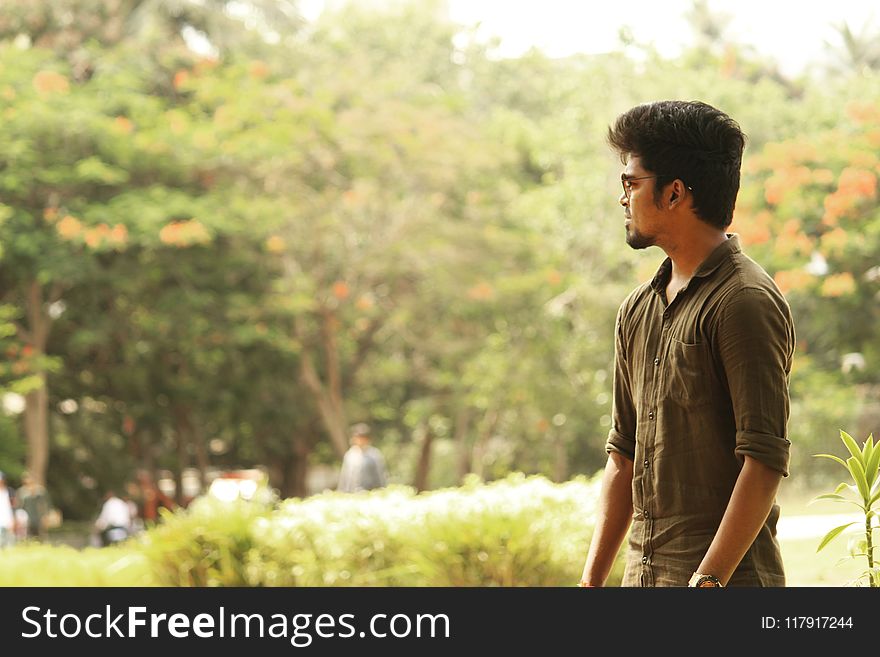 Man In Gray Button-up Shirt Standing Near Bush