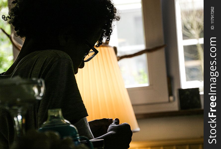 Silhouette of Woman Beside Beige Lampshade Inside White Painted House