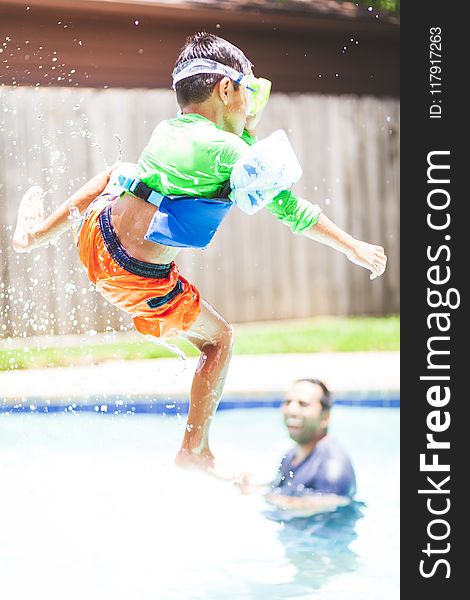 Boy In Green Crew-neck Shirt And Orange Shorts Jump Over Swimming Pool